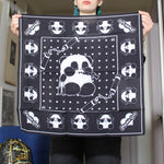 Person holding a black bandana with white designs in a room.