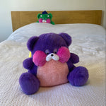 Purple plush toy with pink center on a textured surface