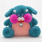 A plush dog toy in teal blue with a pink belly, hot pink cheeks, white horns, and a red collar with a heart-shaped tag, photographed on a clean white background.